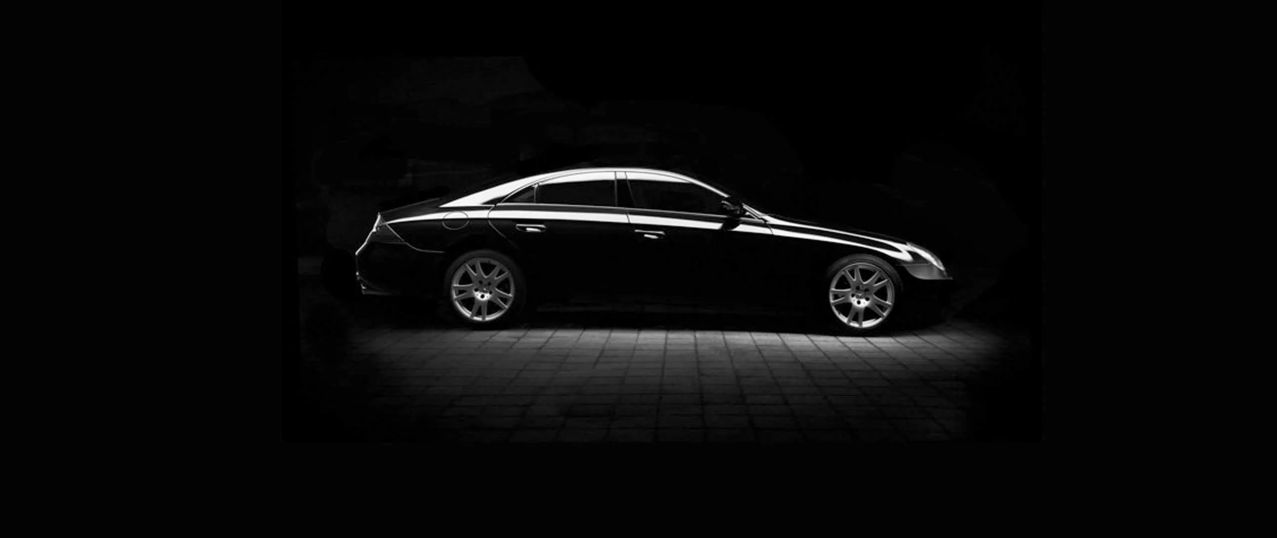 Schwarze Limousine im Dunkeln, von der Seite angestrahlt