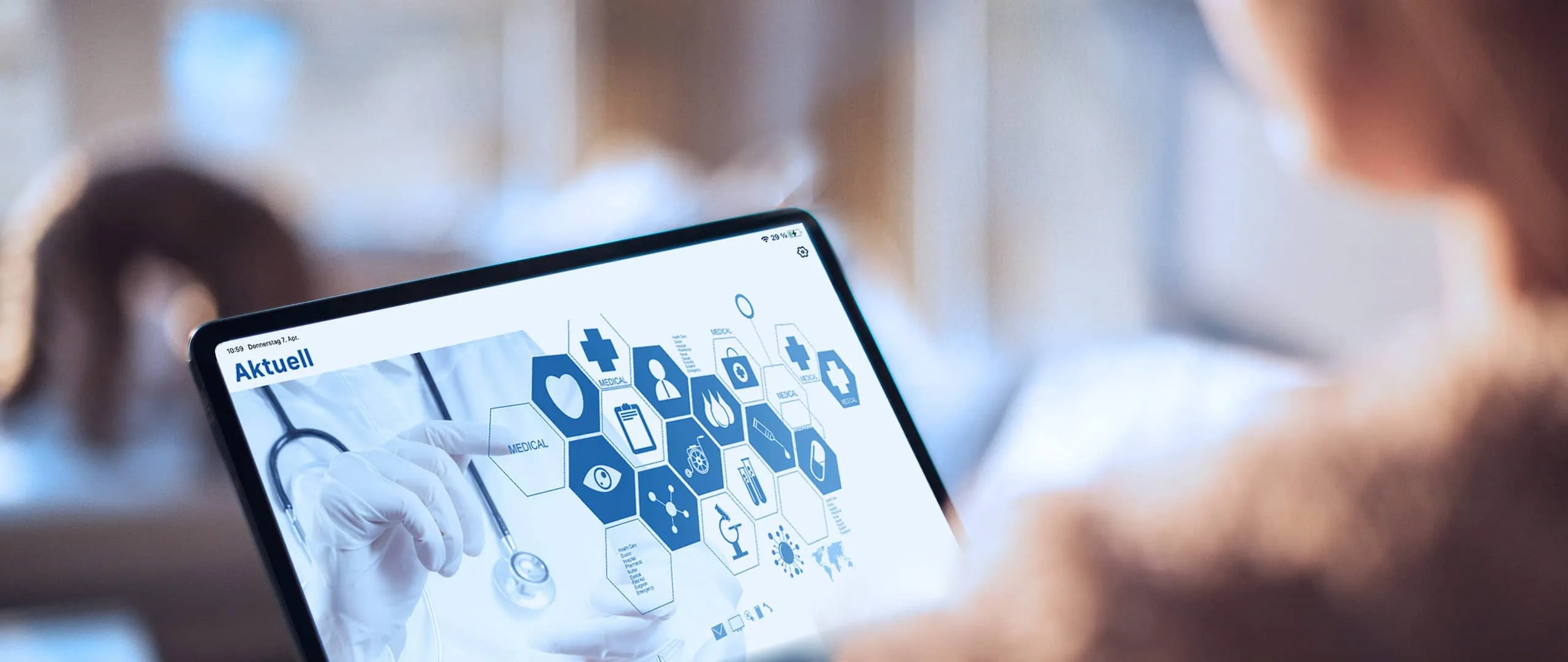 Person liest auf einem Tablet die Rubrik „Aktuell“ der App mit medizinischen Symbolen