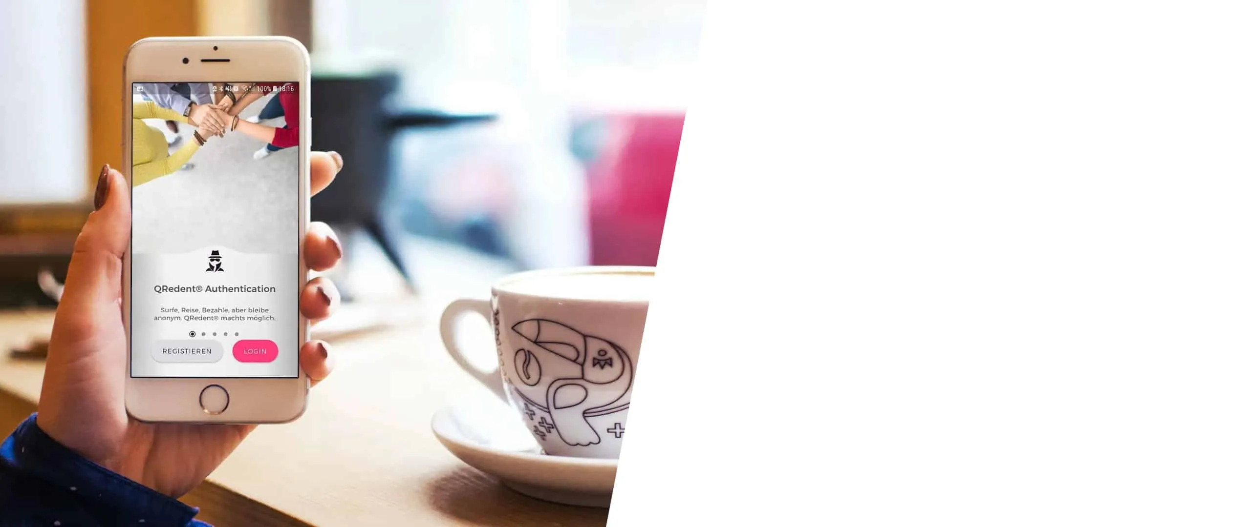 Hand hält ein Smartphone mit dem QRedent-Anmeldebildschirm, im Hintergrund eine Kaffeetasse auf einem Holztisch