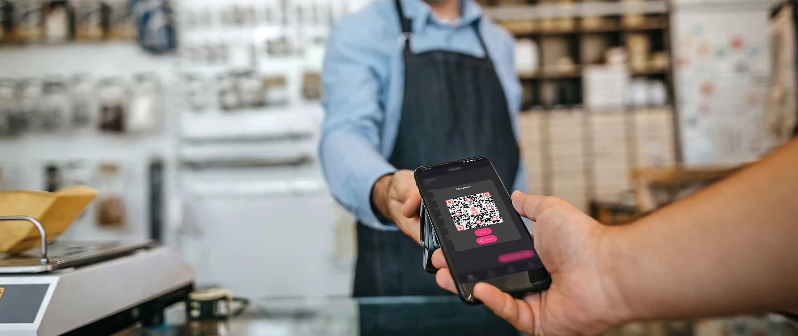 Person übergibt in einem Ladengeschäft ein Smartphone mit einem QR-Code auf dem Display